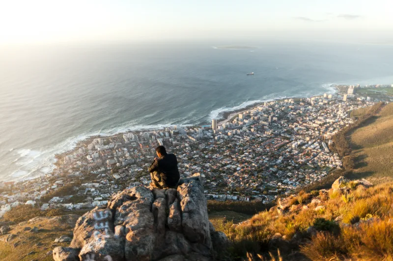 A man sitting high on Lion’s Head, the city and the Atlantic below.