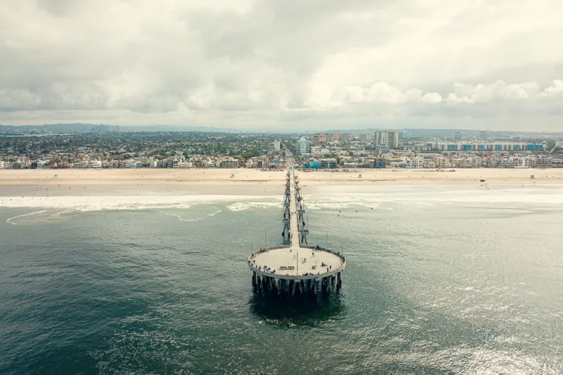Venice Pier reaching out from the beach under heavy cloud, the city spread out behind it.